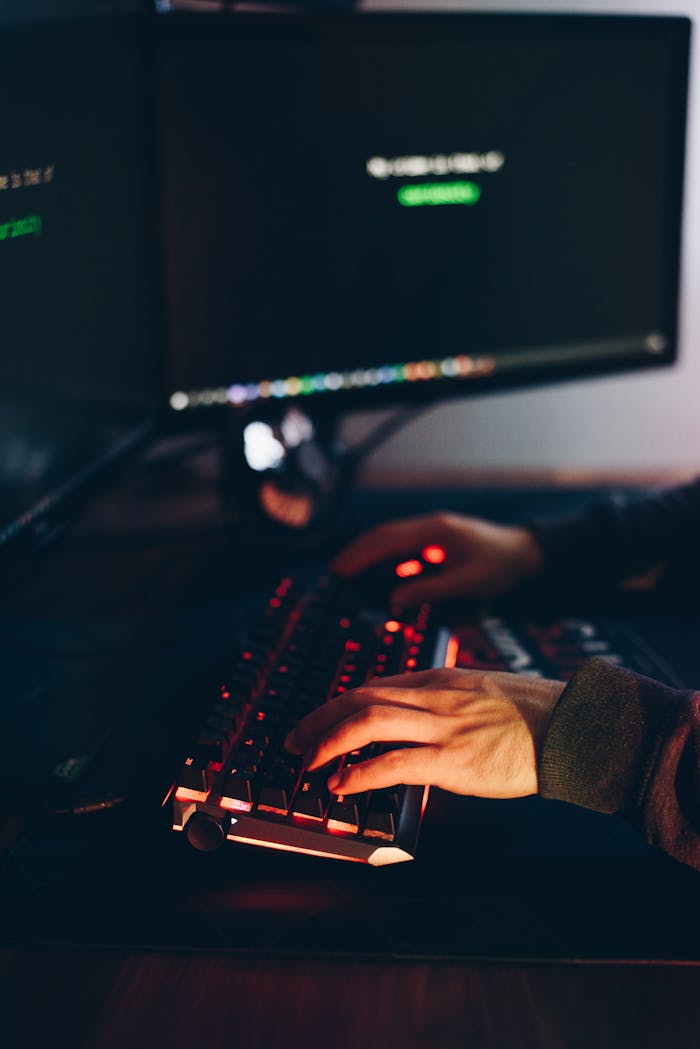 From above of crop anonymous cyber spy typing on computer keyboard with data on screen at night